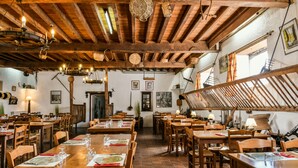 Un restaurante con mesas y sillas de madera, cestas colgantes y un techo rústico.