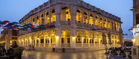 A historic building with multiple balconies and arches, featuring a courtyard with outdoor seating.