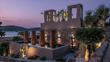Una estructura moderna al aire libre con muros de piedra y grandes jarrones, con vistas a un cuerpo de agua.