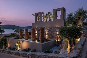 Una estructura moderna al aire libre con muros de piedra y grandes jarrones, con vistas a un cuerpo de agua.