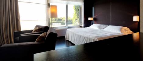 Een hotelkamer met een bed, een bank, een tafel en een raam met gordijnen.