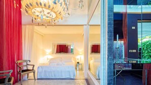 A hotel room with a large bed, a chair, a chandelier, and a mirror. - Riviera Golf Resort (San Giovanni In Marignano)