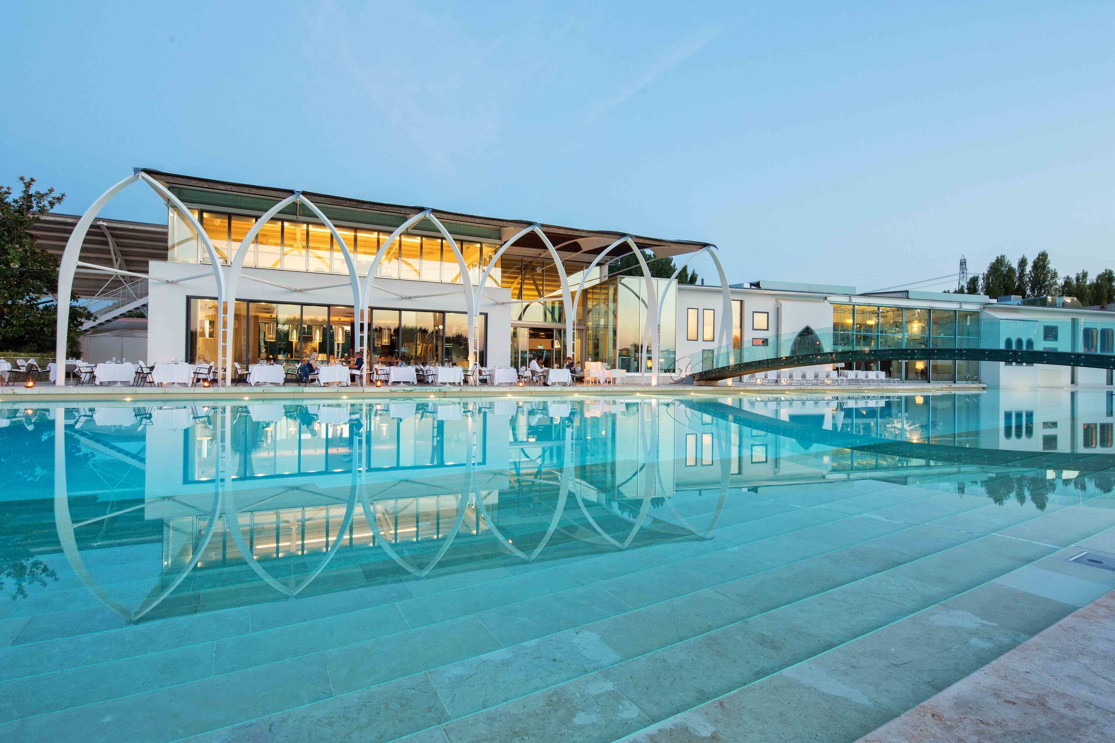 Een modern hotel met een glazen zwembad en een terras.