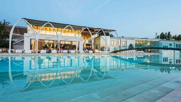 Een modern hotel met een glazen zwembad en een terras.