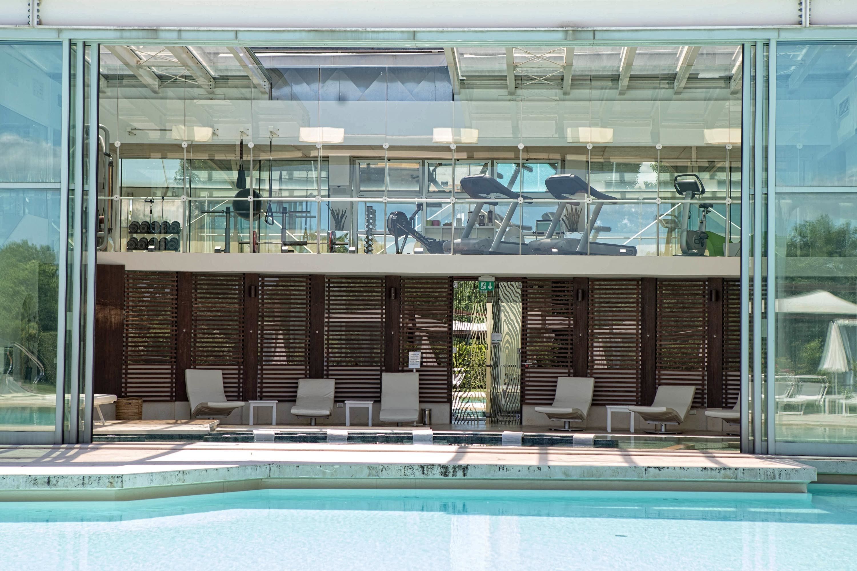 A modern outdoor pool area with lounge chairs and exercise equipment.