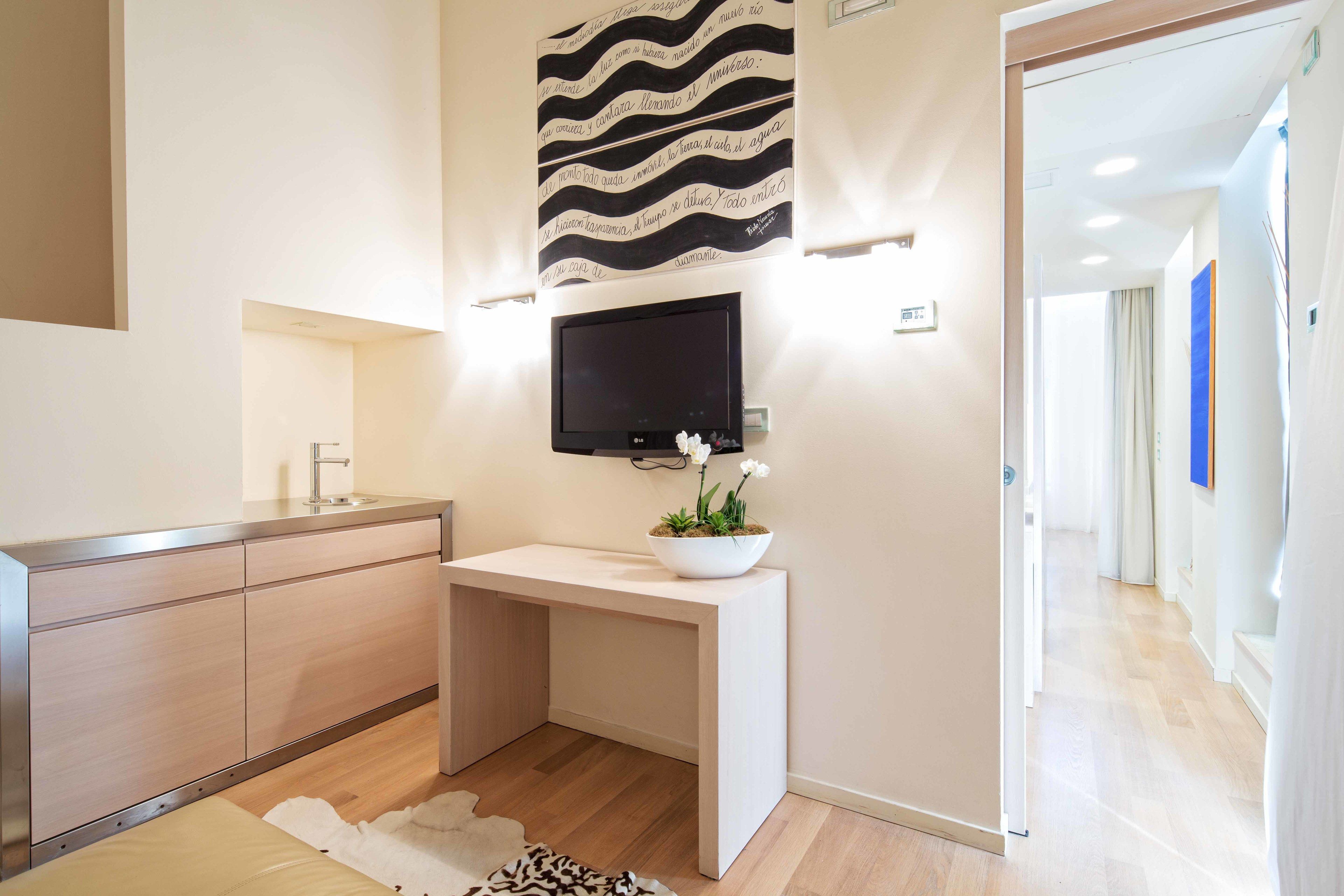 Un baño moderno con tocador de madera, televisor montado y un elemento decorativo en la pared.