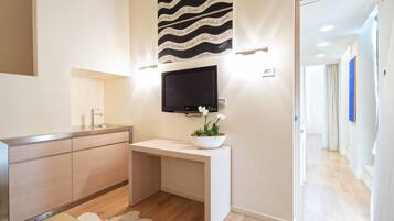 Un baño moderno con tocador de madera, televisor montado y un elemento decorativo en la pared.