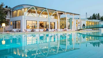 Un hotel moderno con piscina, area relax esterna e facciata in vetro.