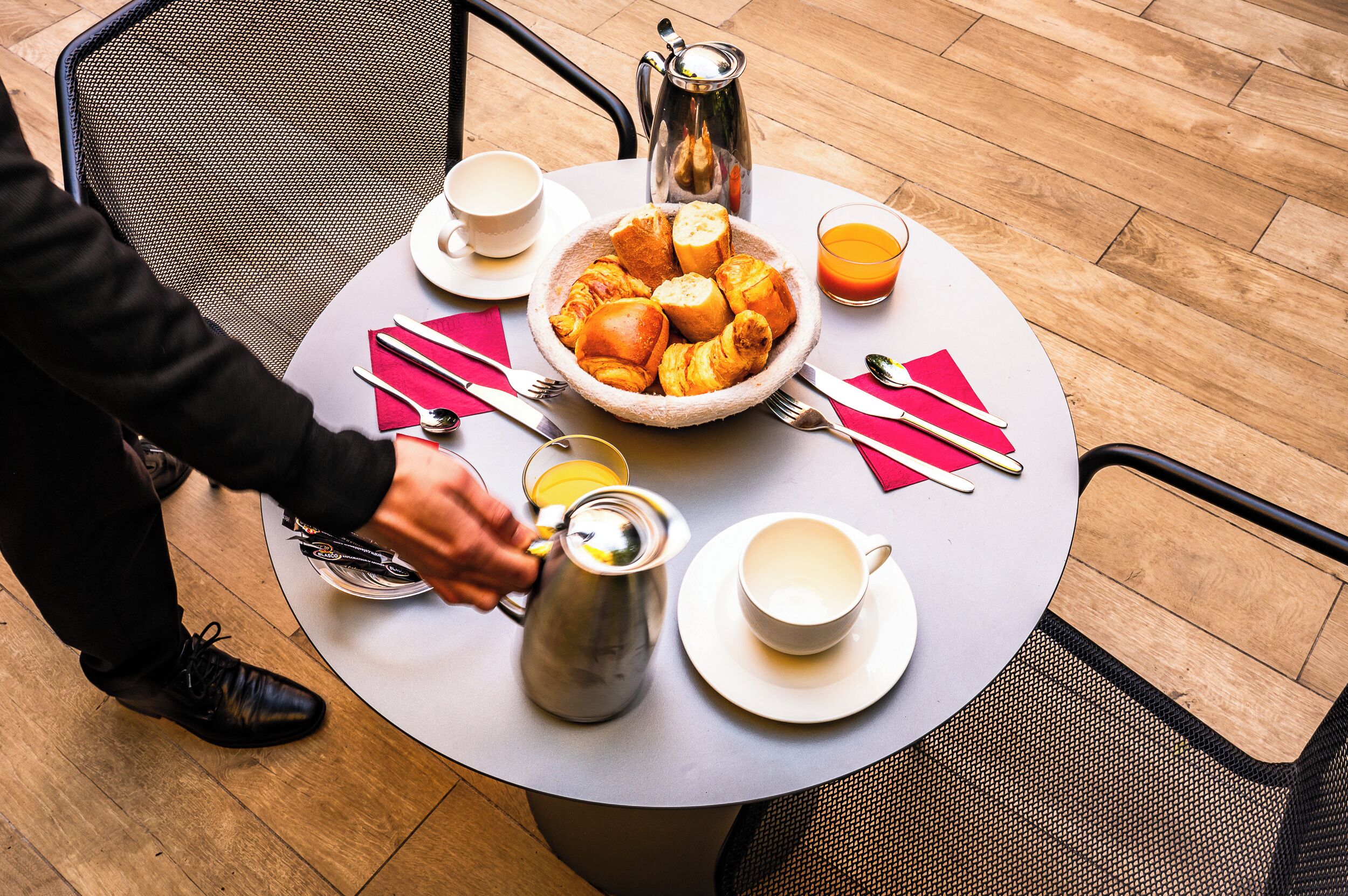 A round table with breakfast items, a coffee pot, and a cup of coffee.