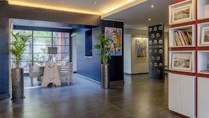 A modern lobby with a reception desk, potted plants, and a bookshelf with framed pictures. - Hôtel Villa Koegui Biarritz (Biarritz)