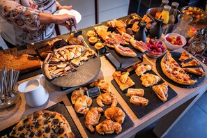 A breakfast buffet with various pastries, sandwiches, and fruits.