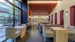 A modern library with bookshelves, seating areas, and large windows. - Hôtel Villa Koegui Biarritz (Biarritz)