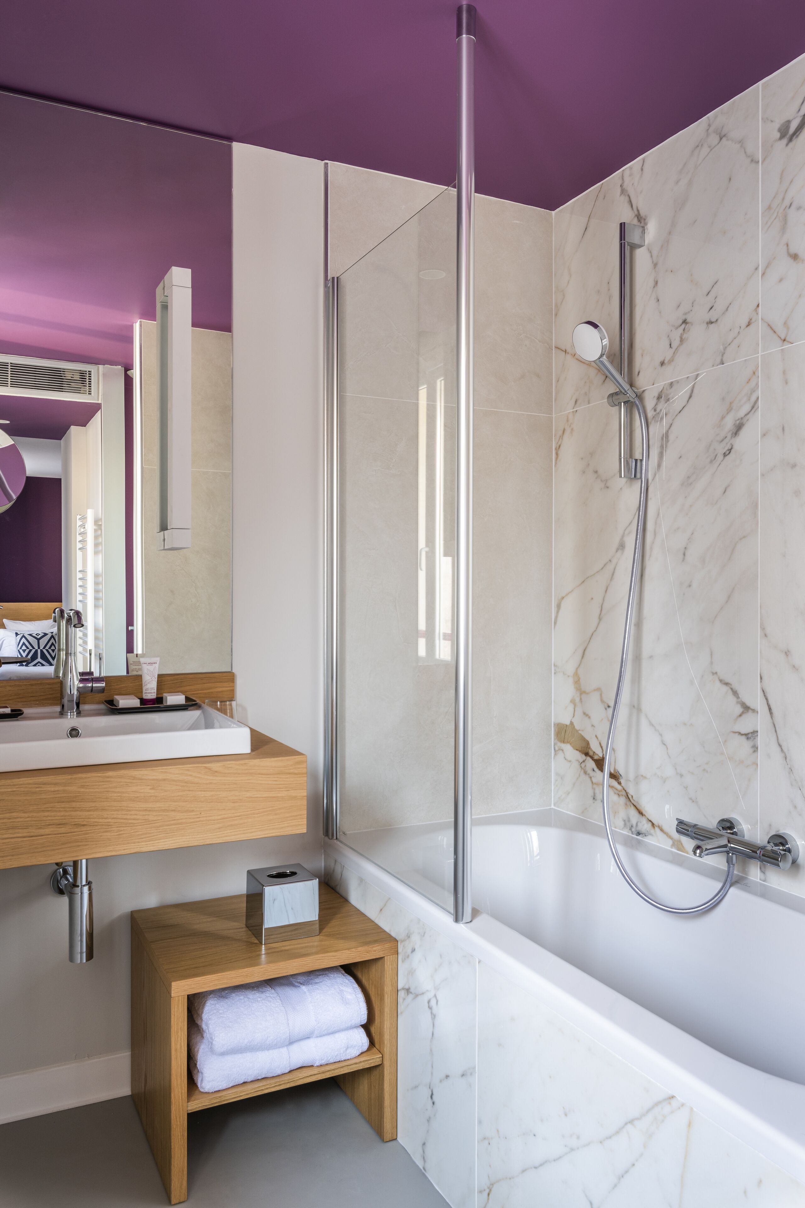 Un baño moderno con una bañera de mármol, ducha con cerramiento de vidrio y tocador de madera.