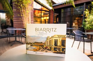 Un libro titulado 'BIARRITZ' con una ilustración de un edificio y una escena frente al mar.