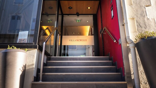 A hotel entrance with a red wall, a staircase, and a sign reading 'Villa Koegui.' - Hôtel Villa Koegui Biarritz (Biarritz)