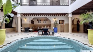 Un espace piscine aménagé avec un coin repas et un escalier menant à un balcon.