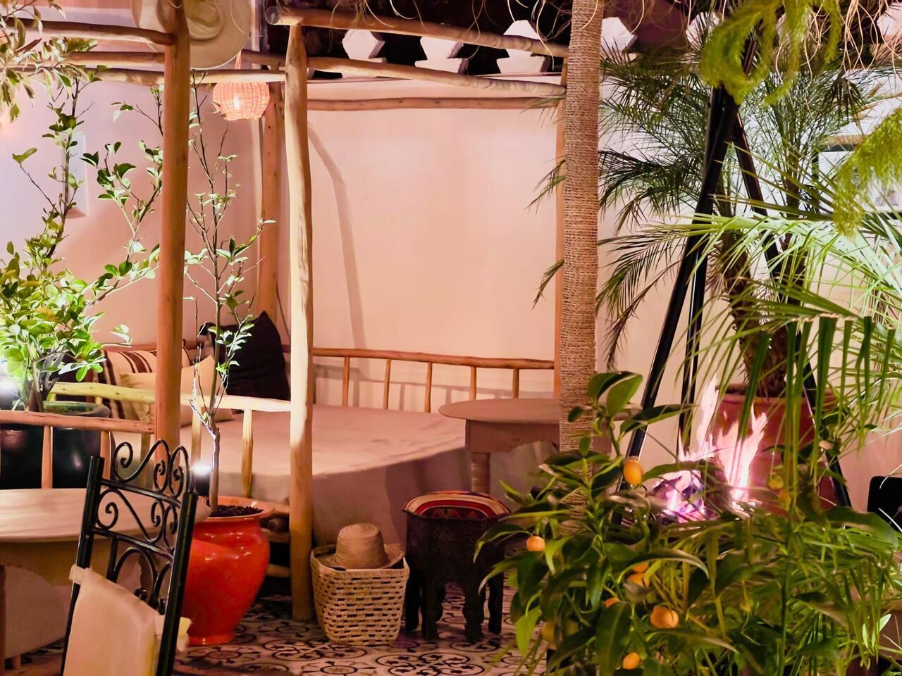 Um jardim interno aconchegante com móveis de madeira, plantas em vasos e uma cadeira de fibra natural.