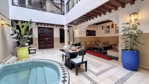 Un espace intérieur vaste et lumineux, doté d’une piscine, de coins salon et de plantes en pot.