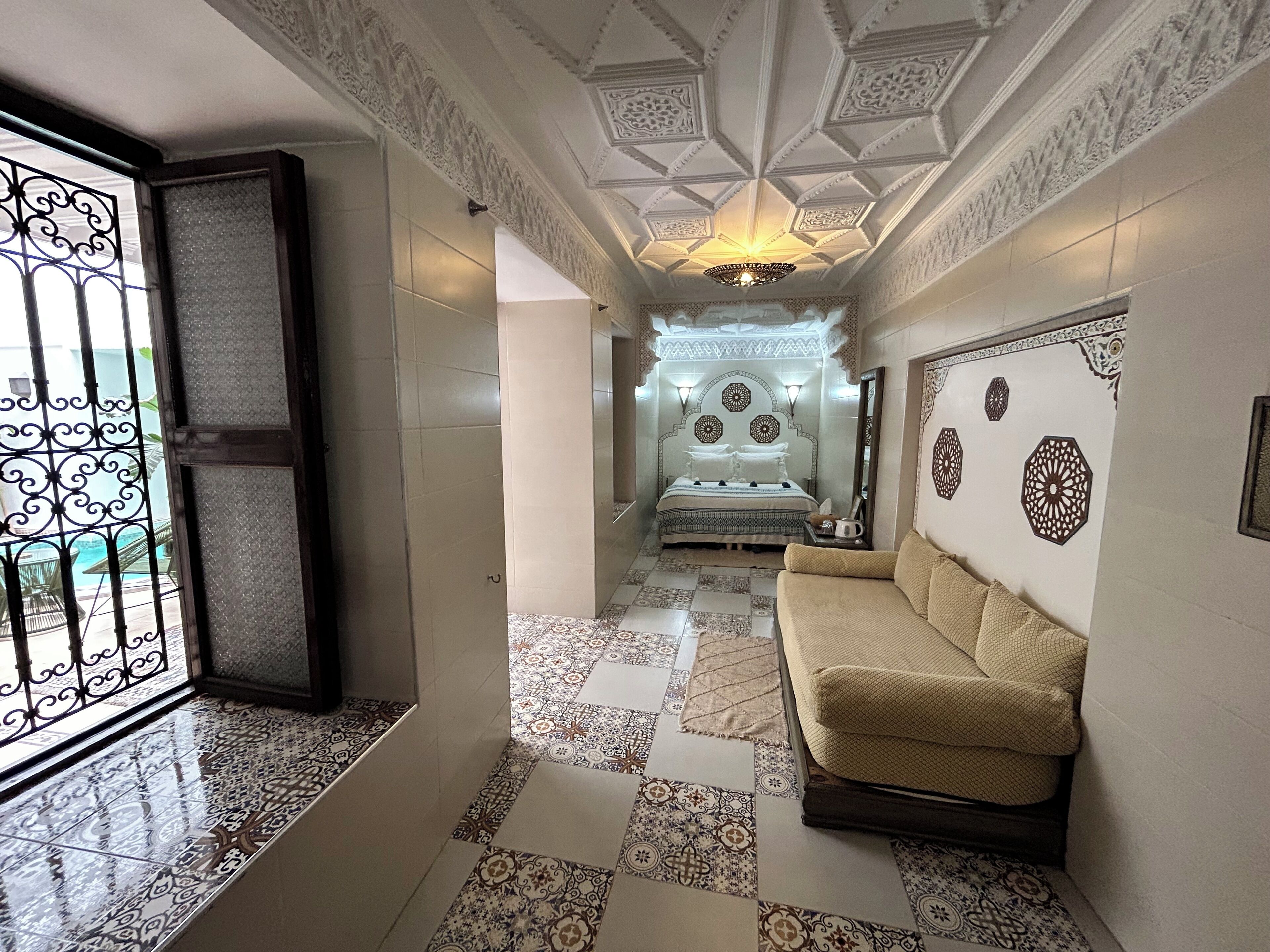 A hallway with patterned tiles, a sofa, and a bed with a decorative headboard.