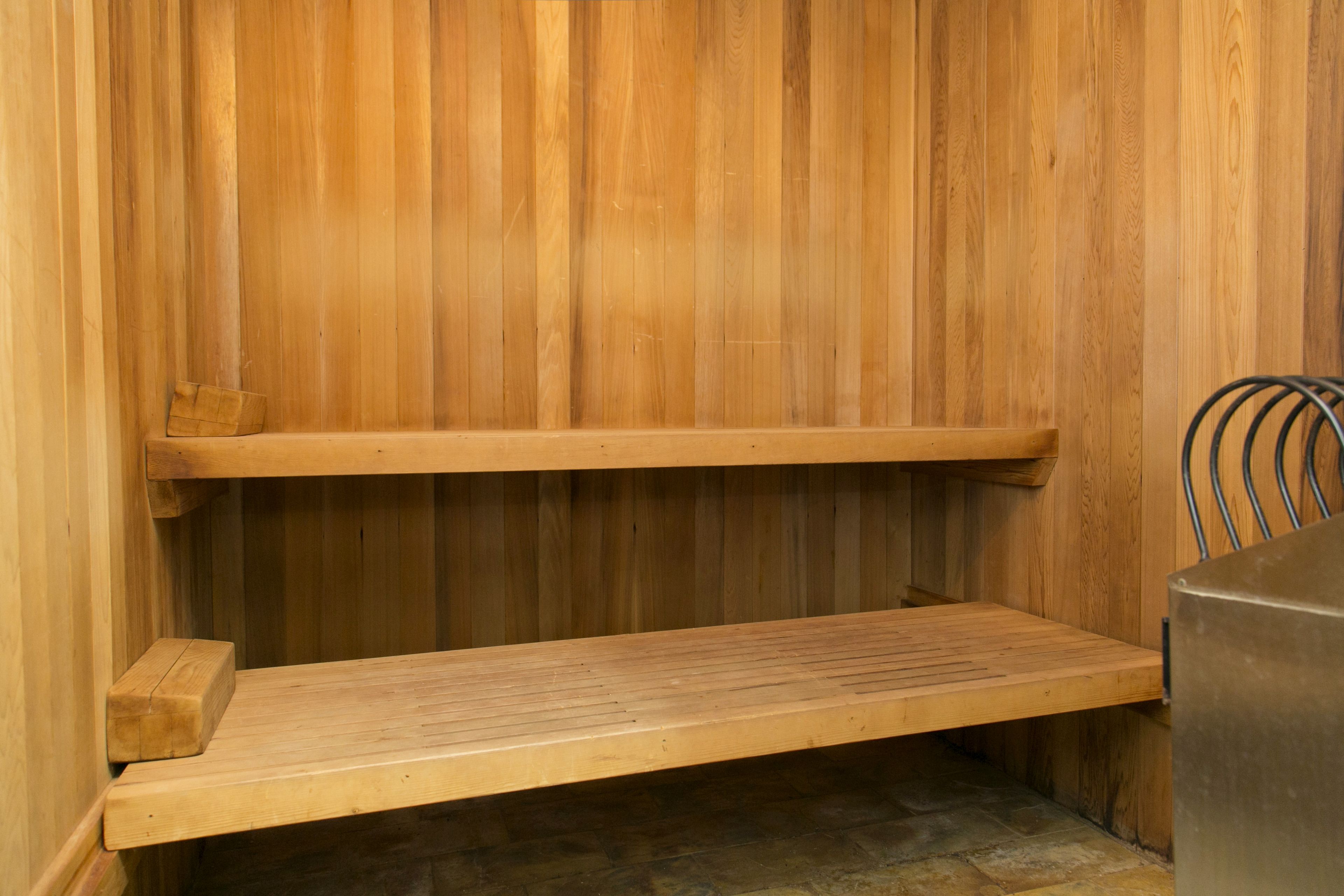 A wooden sauna with two benches and a metal heater.