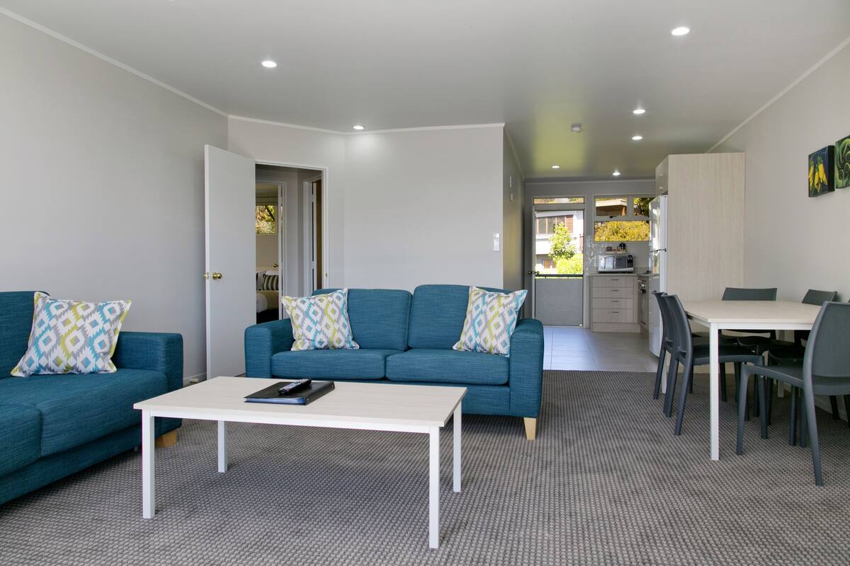 Un salon moderne avec un canapé bleu, une table basse blanche et un coin repas comprenant une table et des chaises.