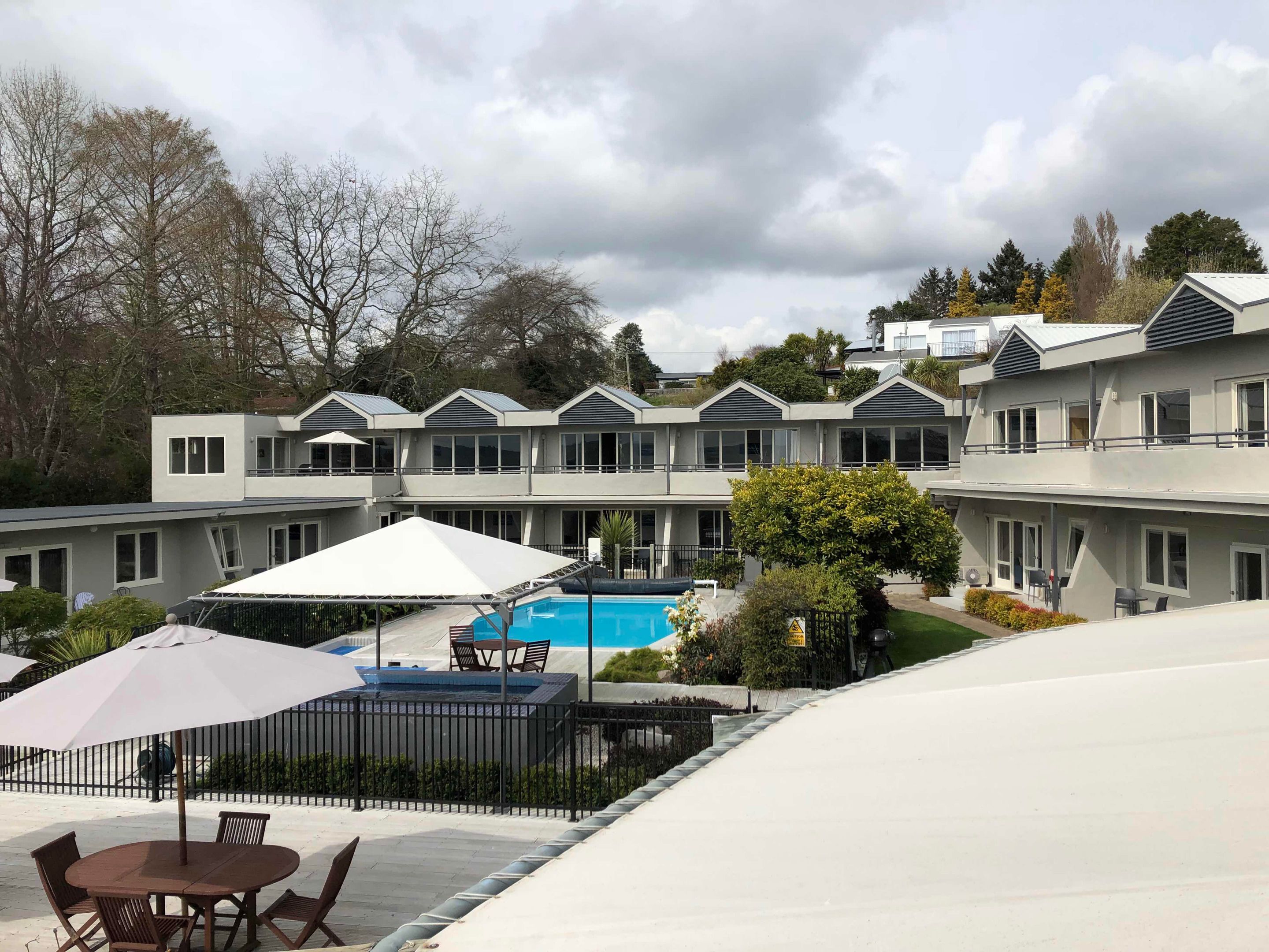 A modern hotel with a pool area, outdoor seating, and a view of the surrounding landscape.
