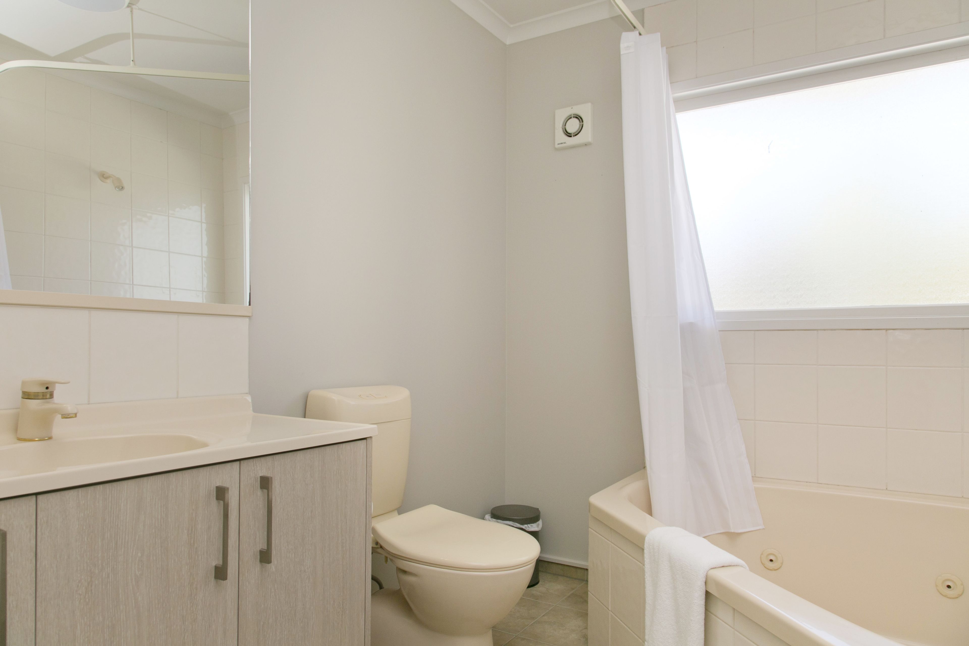 A bathroom with a toilet, sink, cabinet, and bathtub.