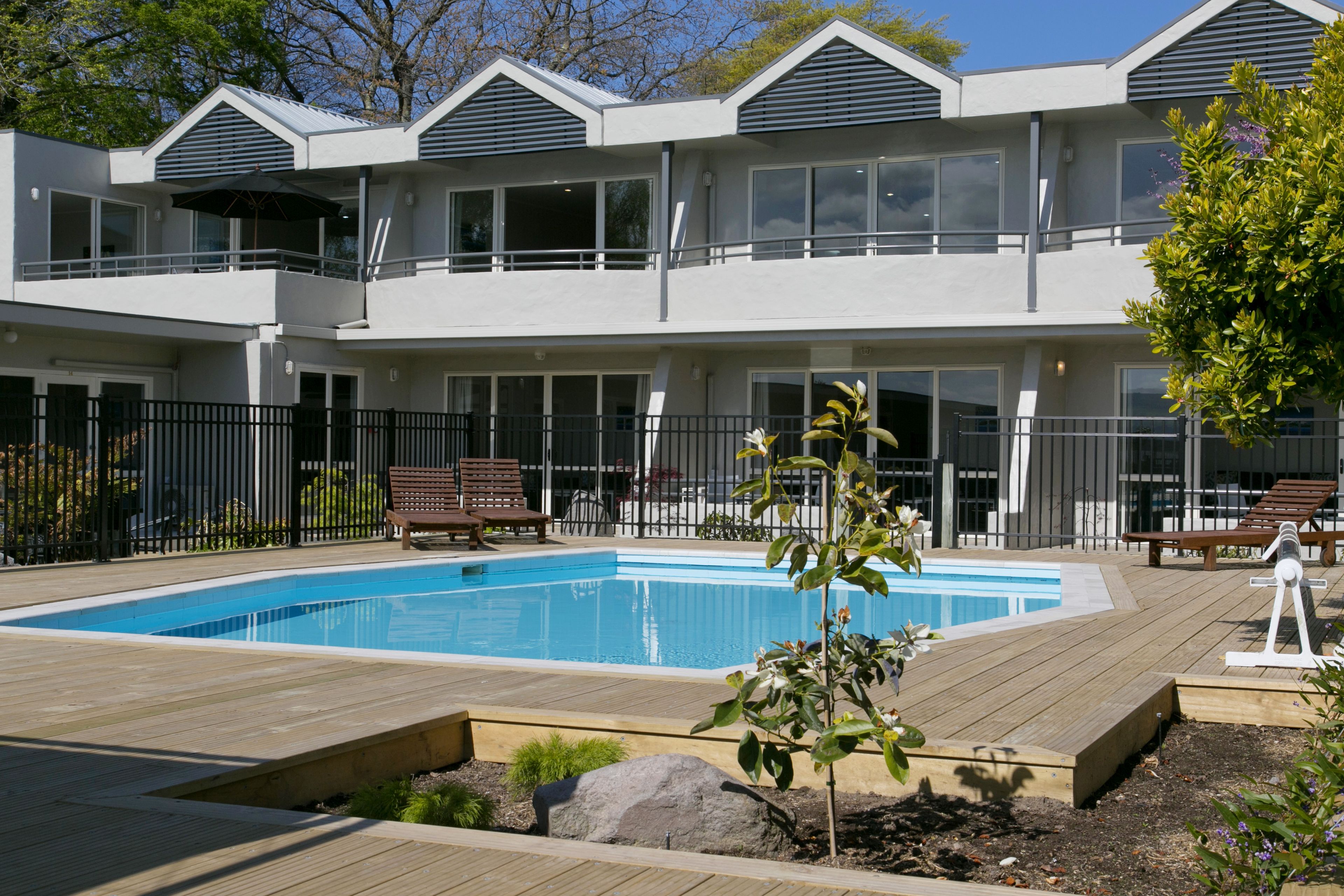 Ett modernt hotell med en swimmingpool, utomhusplats och en välskött trädgård.