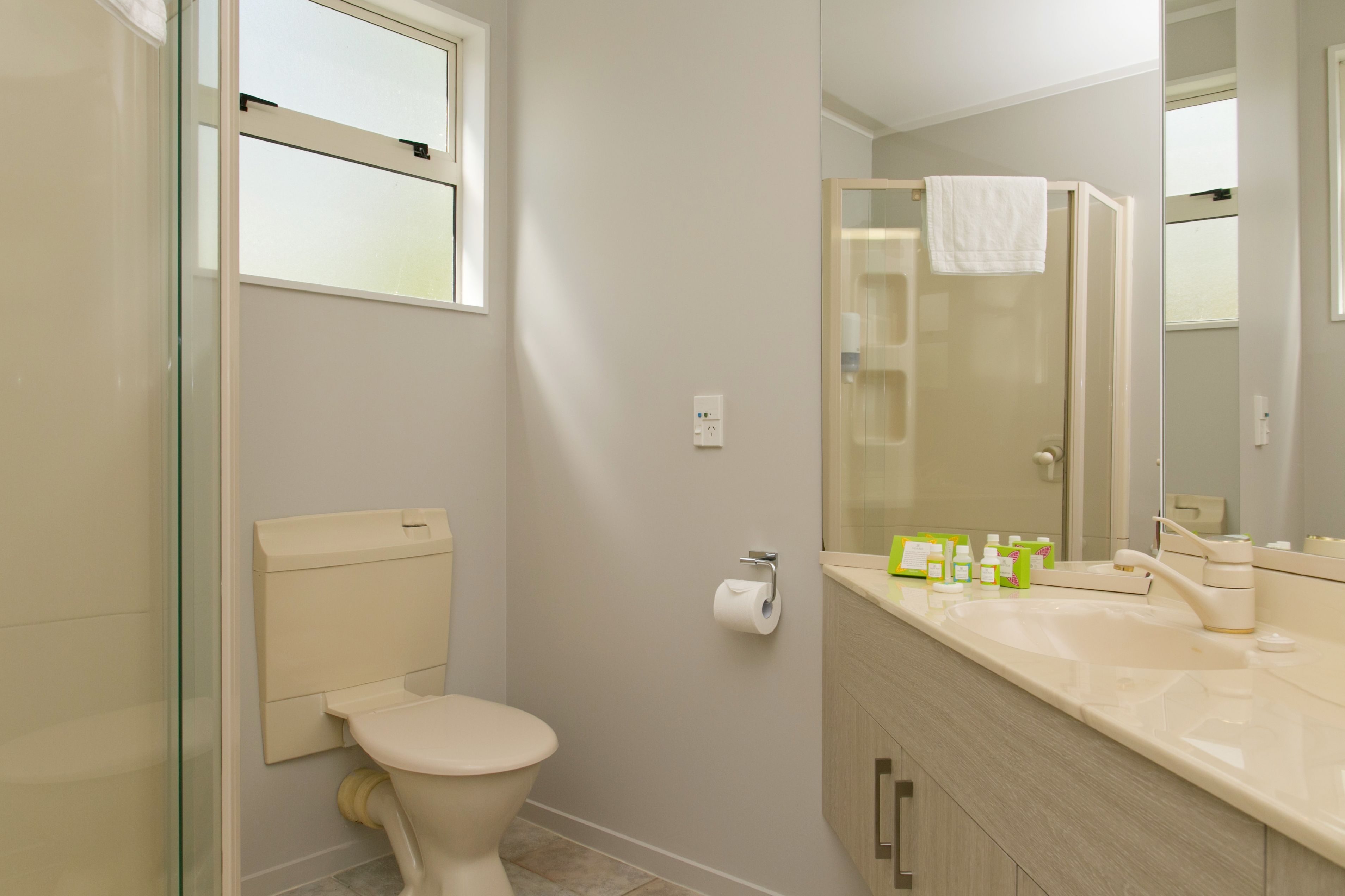 Une salle de bain moderne équipée de toilettes, d’une douche à parois de verre et d’un meuble-lavabo avec des articles de toilette.