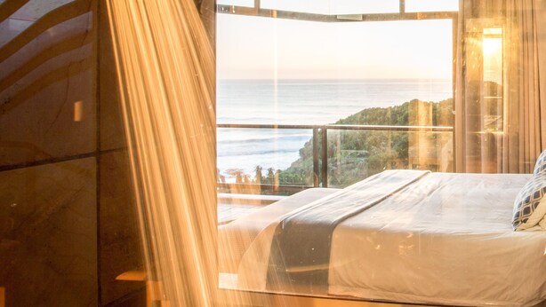 A bedroom with a large window overlooking a coastal view. - Super Tubes Guesthouse (Jeffreys Bay)