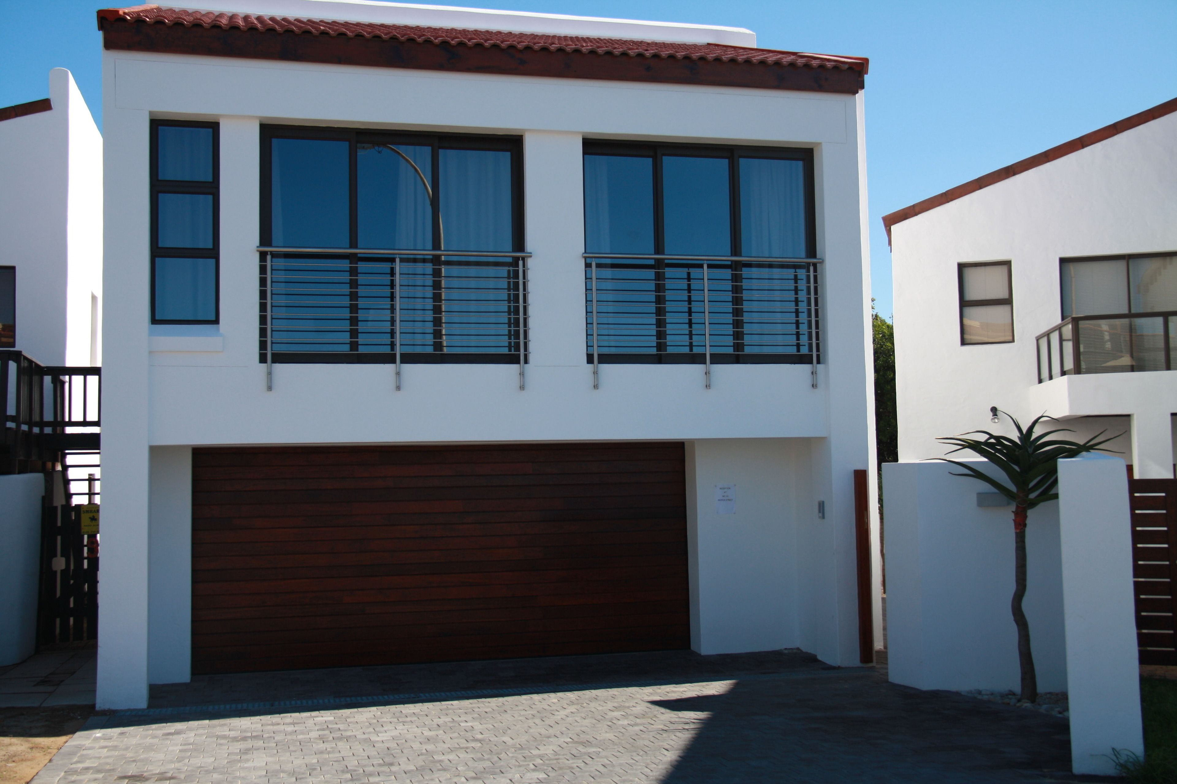 A modern two-story house with a garage, large windows, and a balcony.