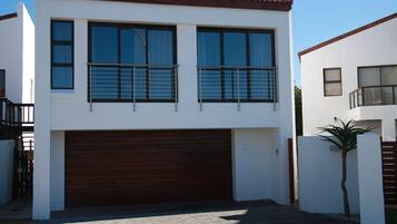 A modern two-story house with a garage, large windows, and a balcony.
