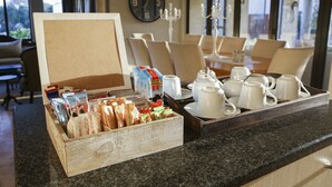 A breakfast buffet setup with a variety of food items and tea sets on a counter. - Super Tubes Guesthouse (Jeffreys Bay)