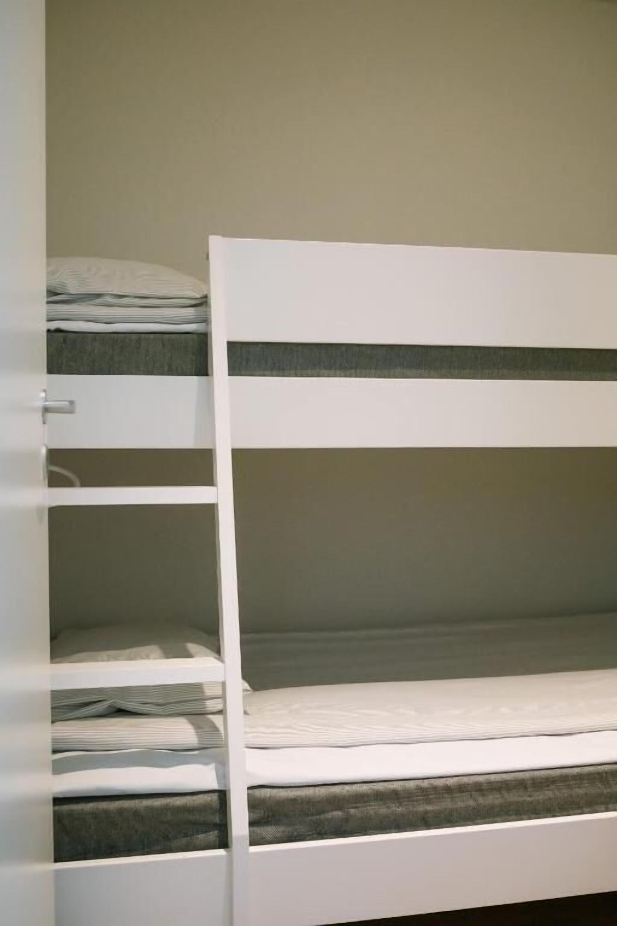 A bunk bed with multiple levels, each with a mattress and pillows.