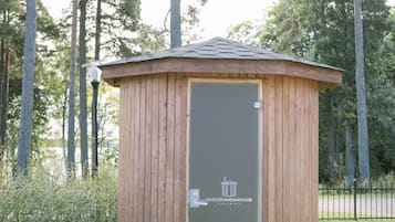 Une petite construction en bois, dotée d’une porte, d’une table ronde et d’une enseigne avec du texte.