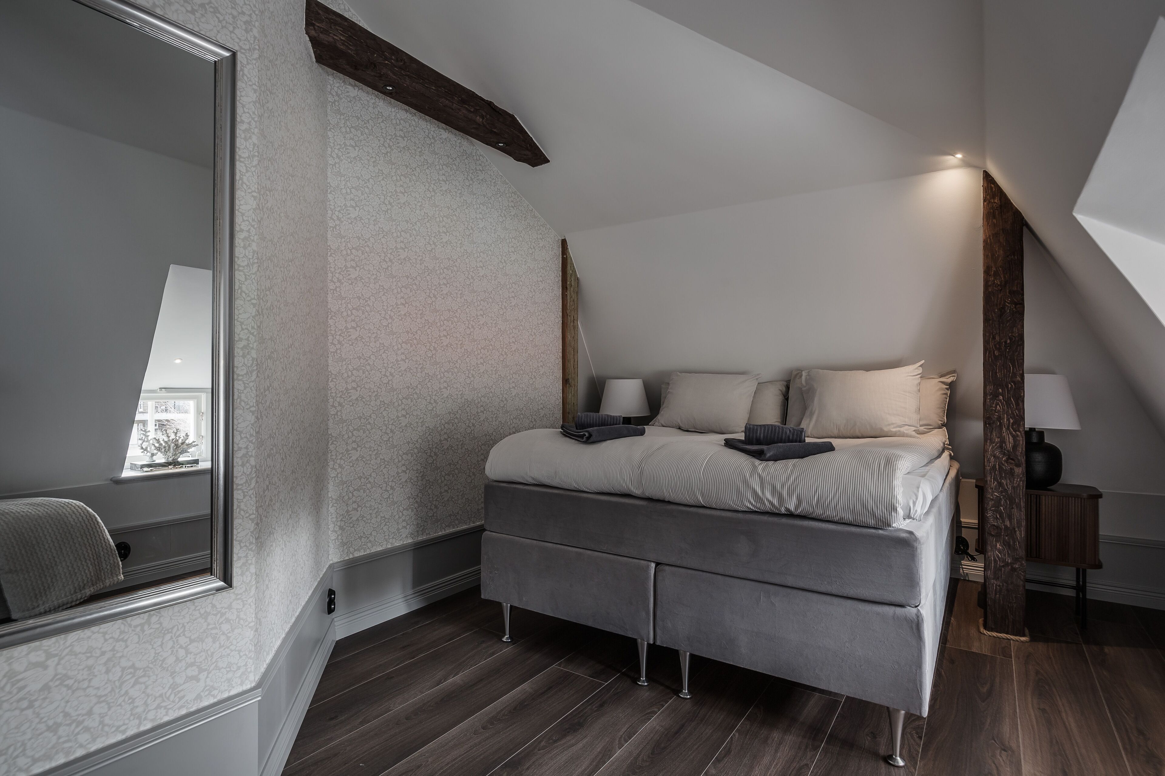Un dormitorio moderno con una cama grande, un espejo y una ventana.
