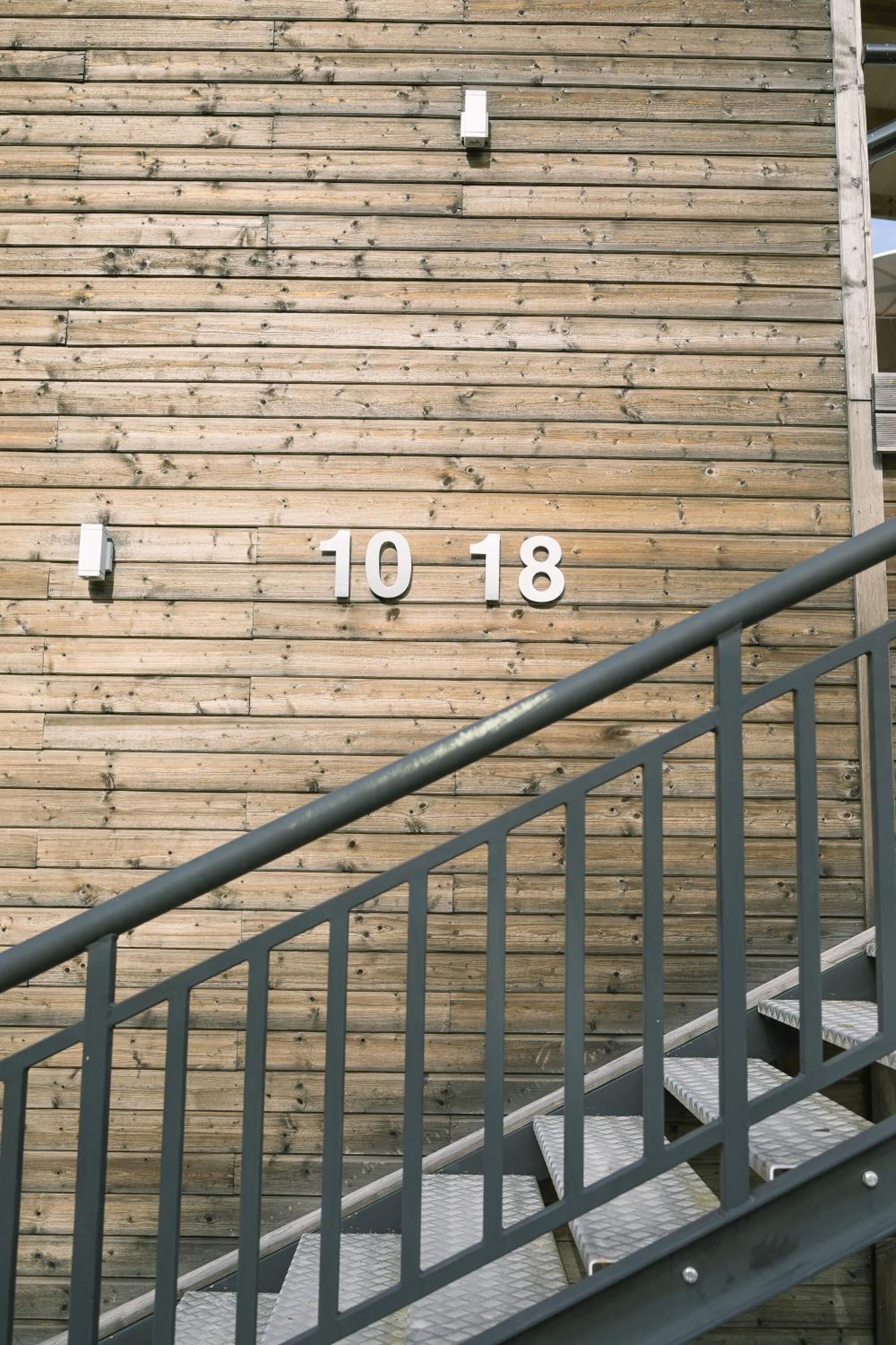 A wooden wall with the numbers "10 18" indicating a room or apartment number.