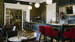 A bar area with a checkered floor, red bar stools, and a bar counter with a mirror and various bottles. - Engeltofta Sea Lodge Hotel (Gävle)