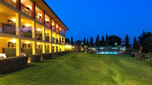 Ein mehrstöckiges Hotel mit Balkonen, einem gepflegten Rasen und Sitzgelegenheiten im Freien.