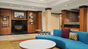 Una sala de estar moderna con chimenea, un sofá azul y una mesa de centro redonda.