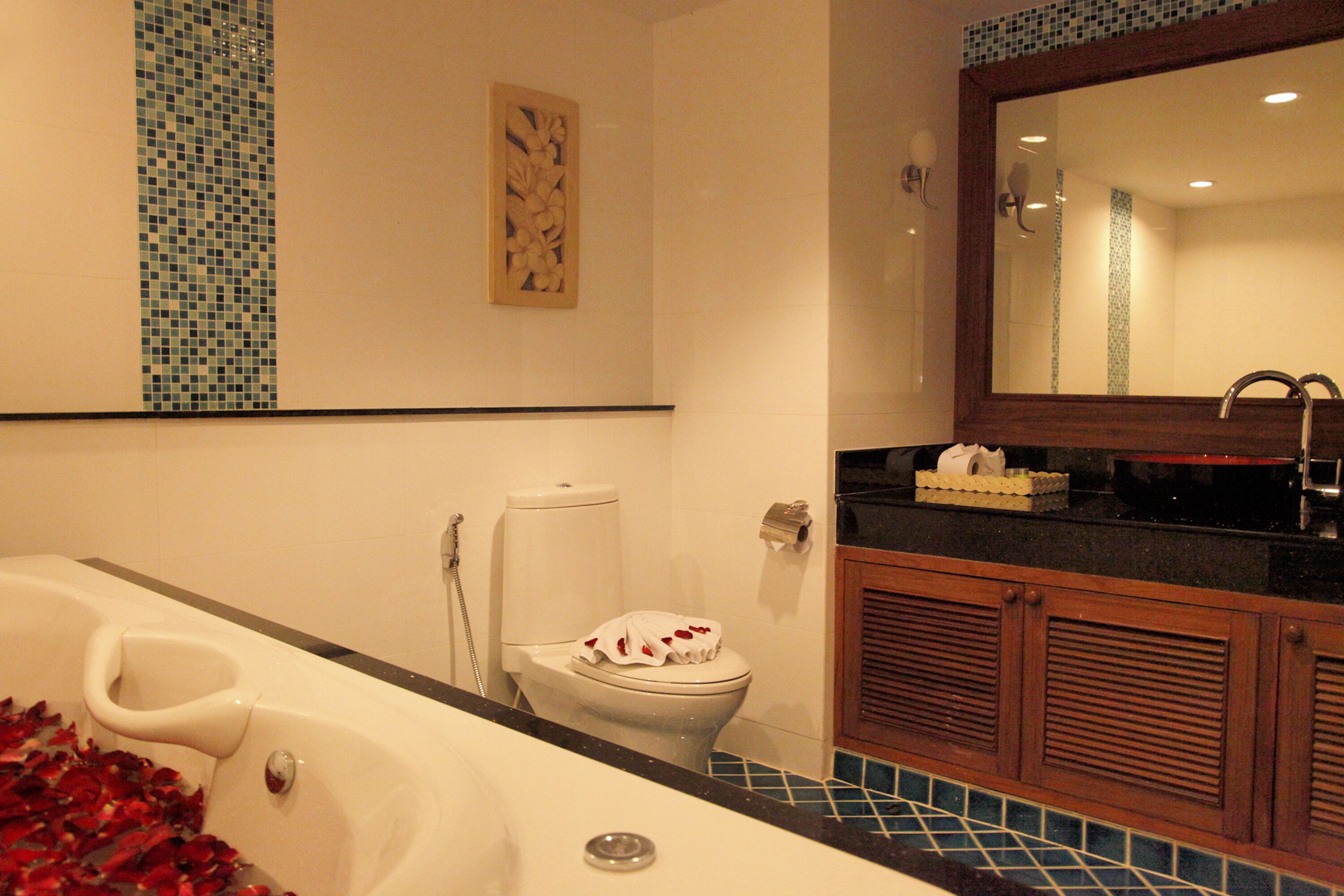 A bathroom with a bathtub, toilet, and wooden cabinets.