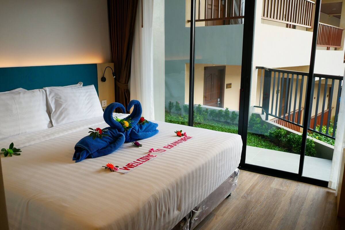 A hotel room with a bed, a welcome sign, and a view of the outdoor balcony.