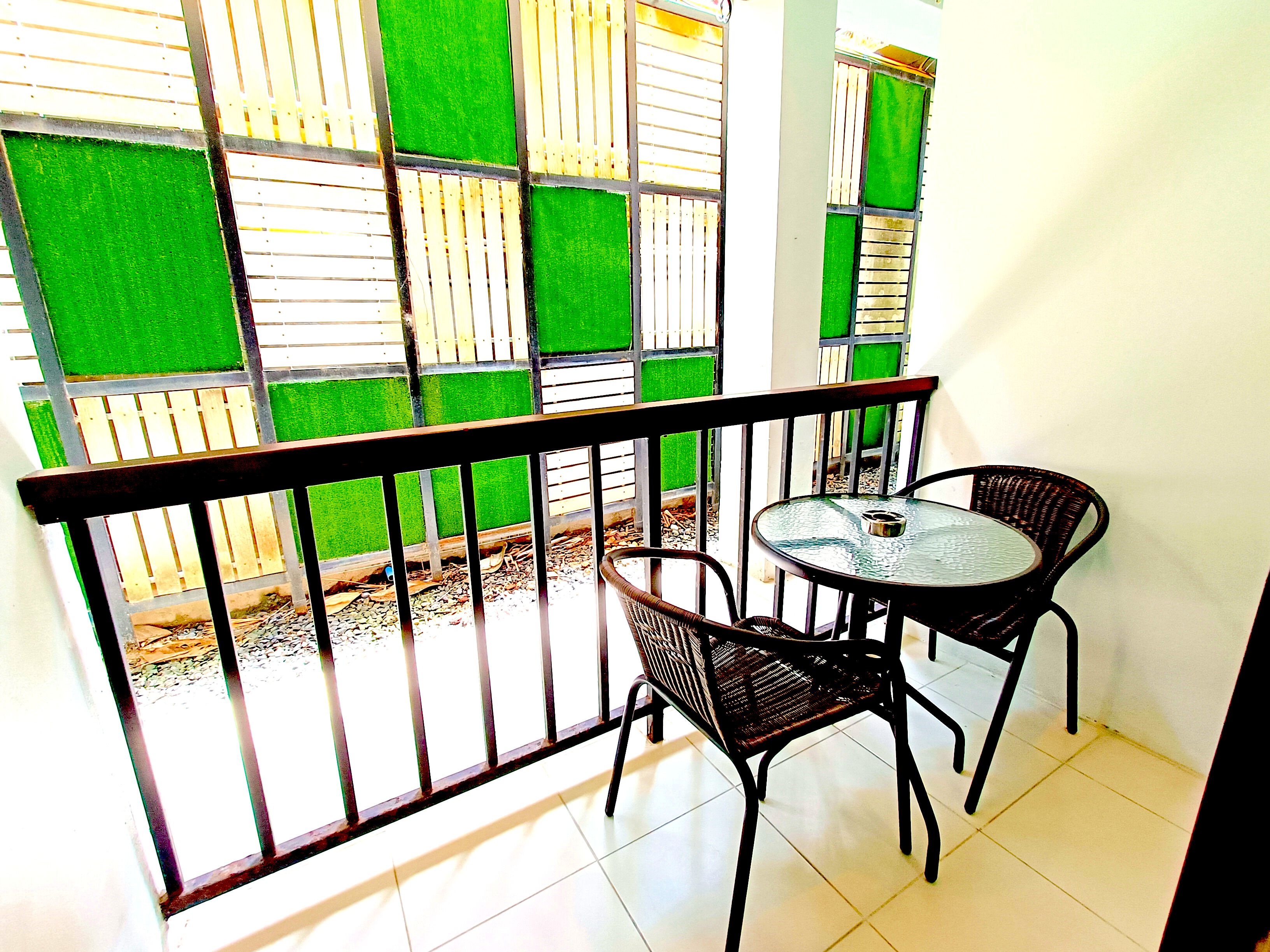 A balcony with a metal railing, two wicker chairs, and a small round table.