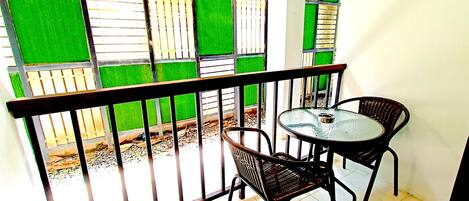 A balcony with a metal railing, two wicker chairs, and a small round table.