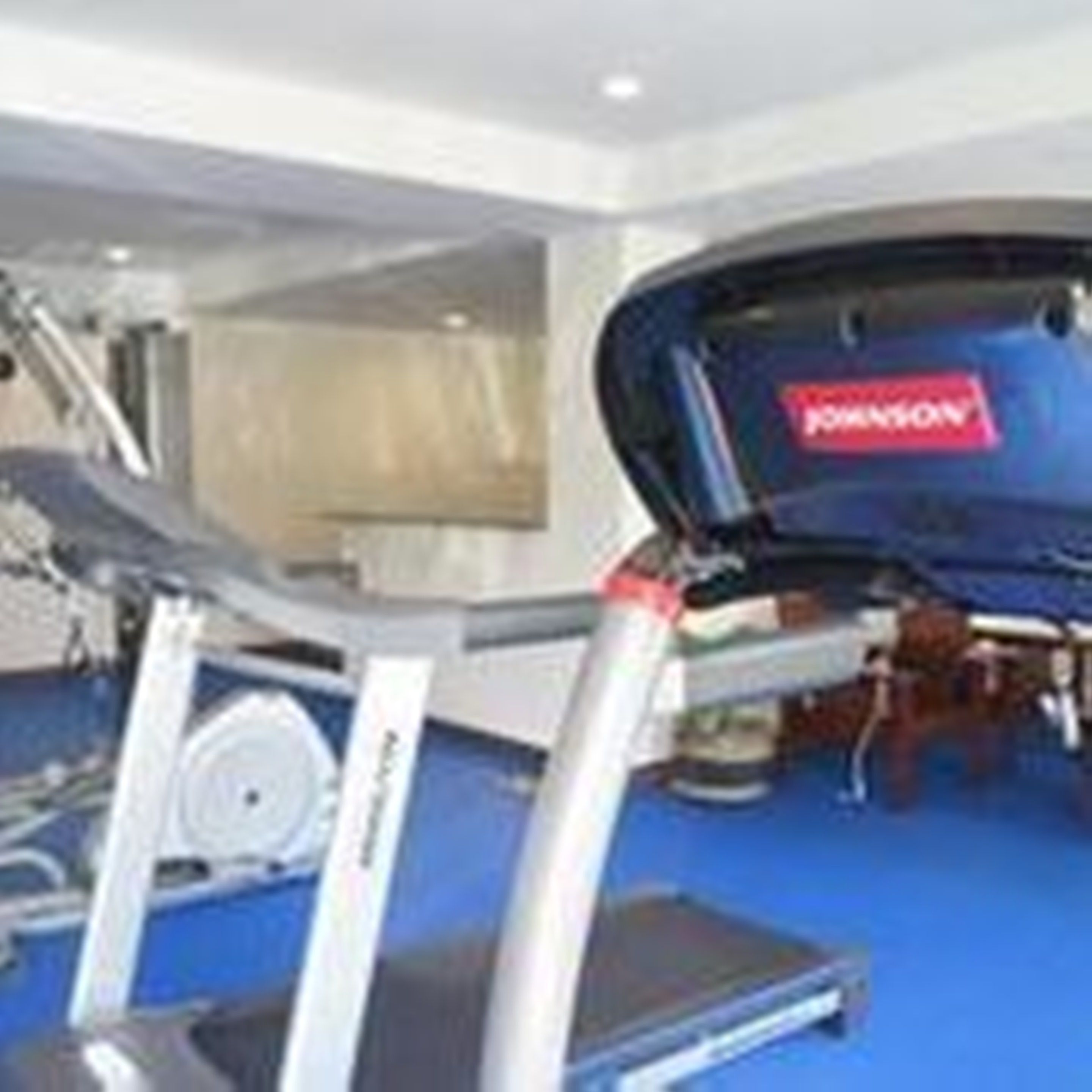 Una palestra con attrezzature per l'allenamento, tra cui tapis roulant e pesi.