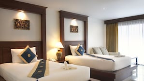 A hotel room with two beds, each with a headboard, bedside tables, lamps, and decorative wall art. - Baan Yuree Resort and Spa (Patong)