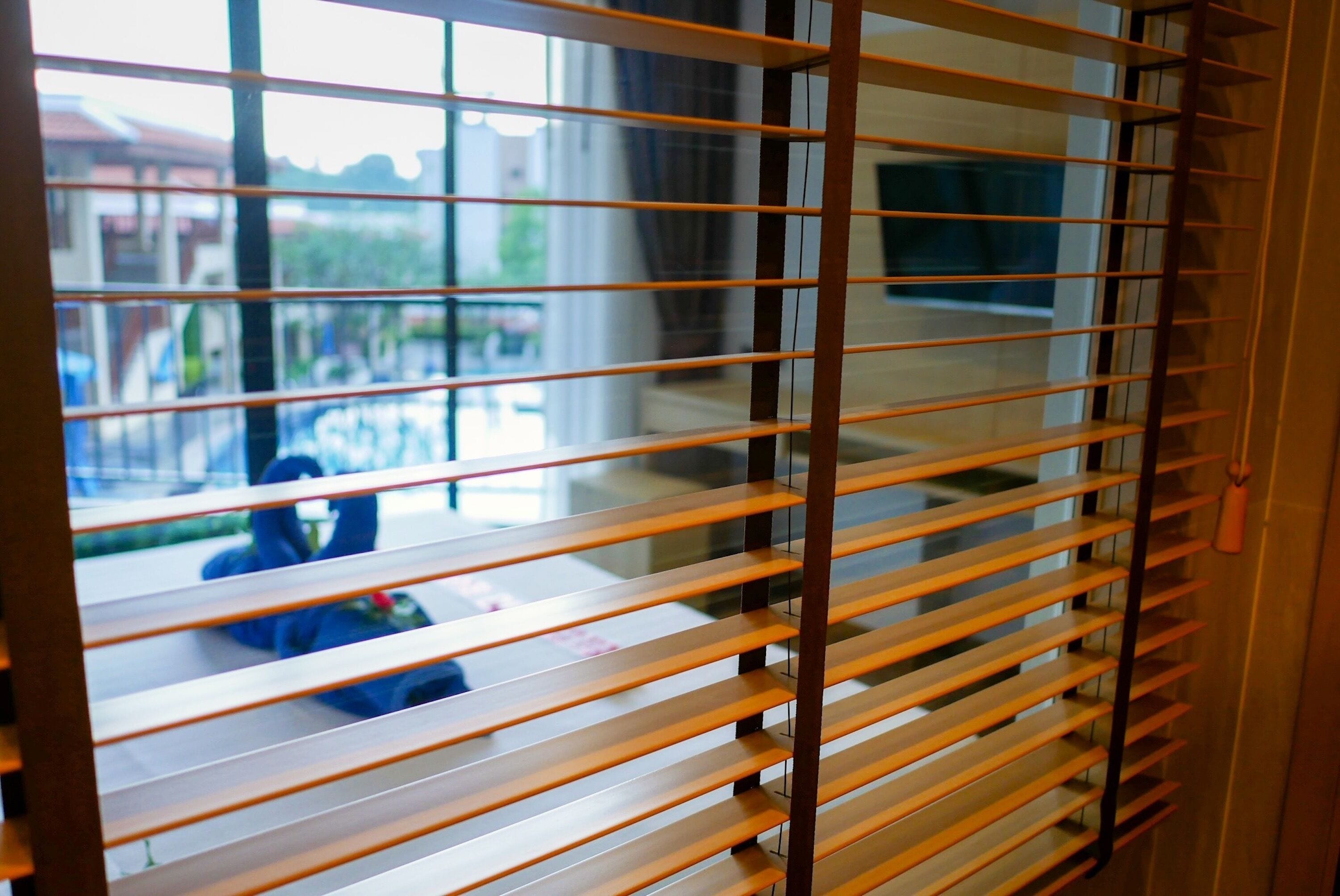 Una habitación con persianas horizontales, un ventanal y vistas al exterior.