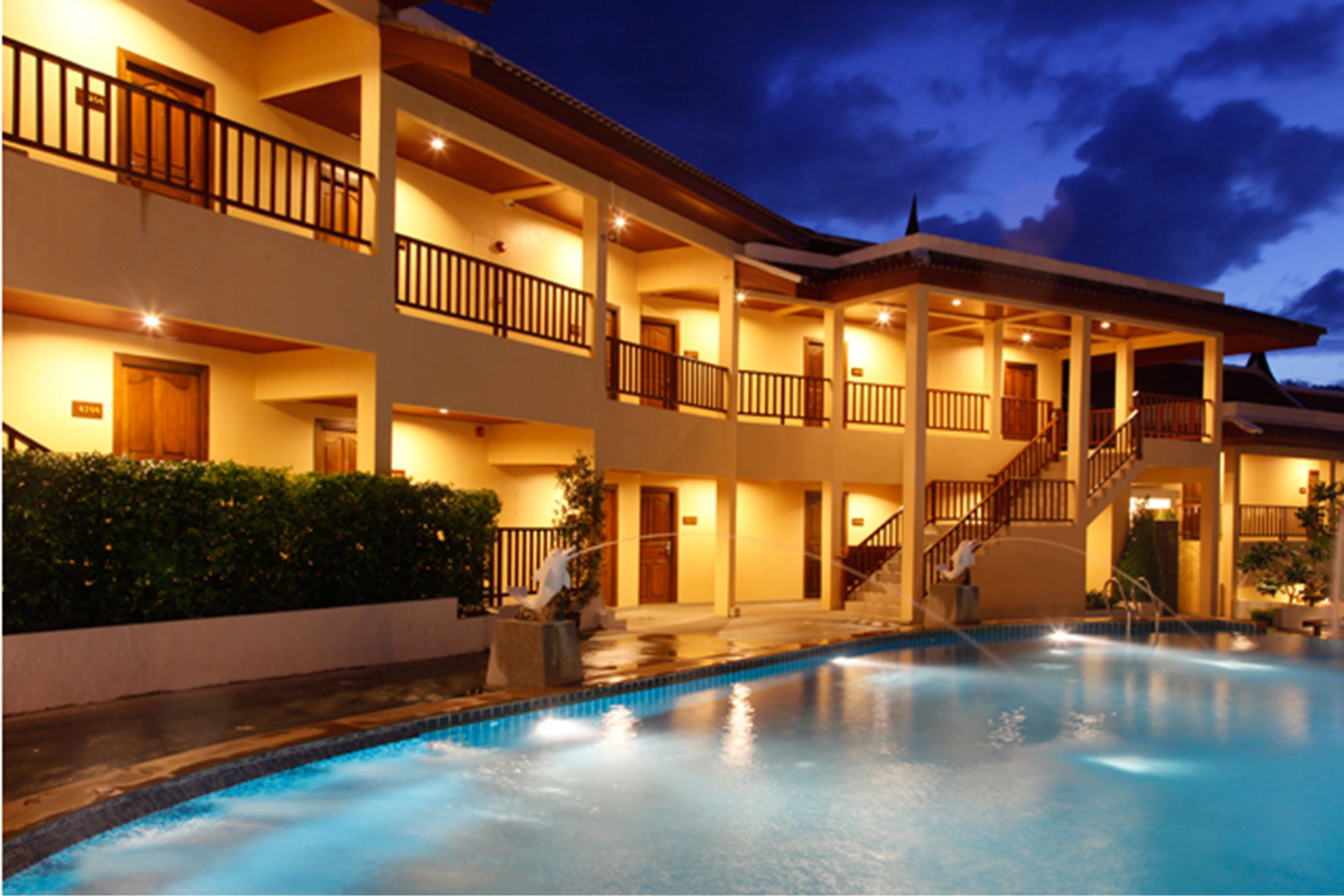 Un hotel de varios pisos con piscina, balcones y una zona exterior cubierta.