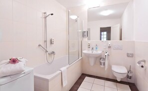 Une salle de bain moderne équipée d’une baignoire, d’une douche, d’un lavabo et de toilettes.