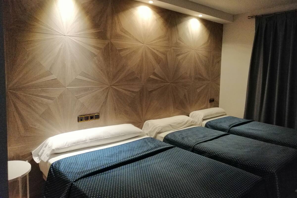 Habitación de hotel con diseño moderno, que incluye una cama grande con dos almohadas y cabecero a juego.